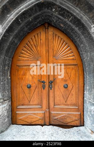 Vecchia porta in legno con arco rotondo e decorazioni. Ampia entrata rustica in grigio marrone. Foto Stock