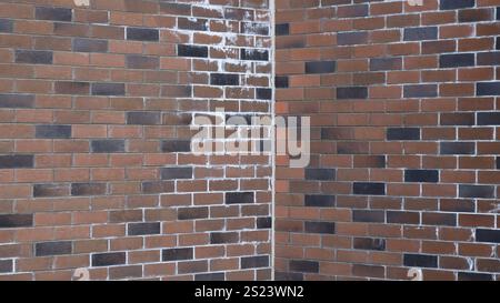 angolo di due muri in mattoni fatti di blocchi marrone scuro con inclusioni nere e tracce bianche di calce, sfondo grafico in muratura dai toni scuri Foto Stock