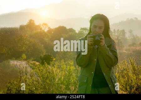 Una donna che scatta foto del tramonto su una vetta di una montagna durante un viaggio in campeggio Foto Stock
