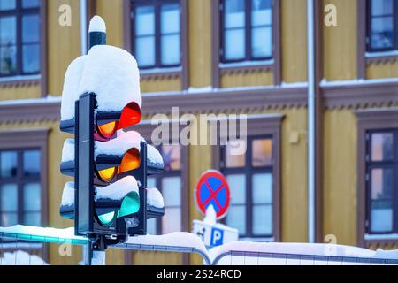 I semafori stradali sono ricoperti di neve, dove tutti i semafori (rosso, ambra e verde) sono accesi contemporaneamente. Foto Stock