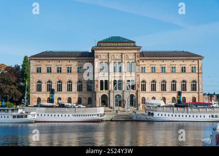 Museo nazionale svedese a Stoccolma, con traghetti per pendolari e turisti parcheggiati di fronte. Colori autunnali, sole brillante. Foto Stock