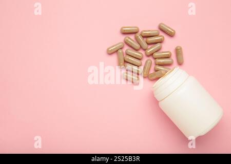 Pillole e bottiglia di medicina farmaceutica beige su sfondo rosa. Vista dall'alto Foto Stock