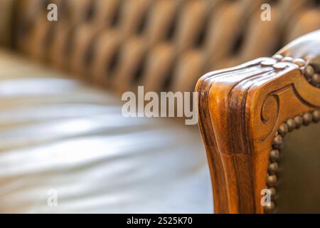 Una vista ravvicinata di un'elegante sedia in pelle verde che presenta un bracciolo in legno dal design splendido. La sedia è collocata in un ambiente interno ben illuminato Foto Stock