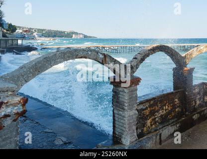 Tempesta di mare, rovinato pier e schizzi di surf davanti (Mar Nero, Bulgaria, vicino a Varna). Foto Stock