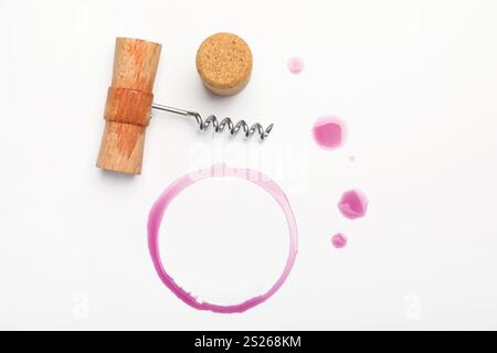 Cavatappi, sughero e macchie di vino rosso su sfondo bianco, vista dall'alto Foto Stock