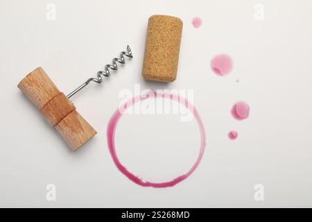 Cavatappi, sughero e macchie di vino rosso su sfondo bianco, vista dall'alto Foto Stock