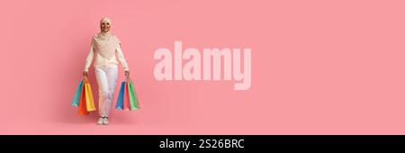 Allegra giovane donna musulmana che cammina con le borse della spesa Foto Stock