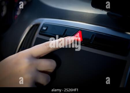 Primo piano della giovane donna premendo il pulsante di emergenza in auto Foto Stock