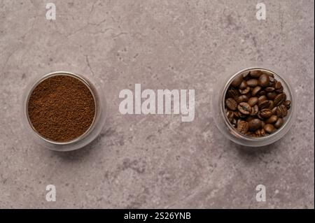 Vista dall'alto, caffè macinato e a grana aromatica in bicchieri su diversi lati, cemento grigio. Copia spazio sfondo, copertina, sfondo Foto Stock