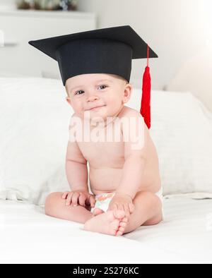 Tonica ritratto di adorabili sorridente baby boy in graduazione hat cercando nella fotocamera Foto Stock