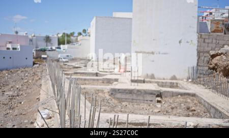 Cantiere sfocato con fondamenta di edifici sfocate e sfondo sfocato che suggerisce lo sviluppo in corso in condizioni di cielo limpido Foto Stock