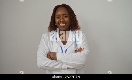 Giovane donna afroamericana medico con braccia incrociate che sorride con fiducia su uno sfondo bianco isolato Foto Stock