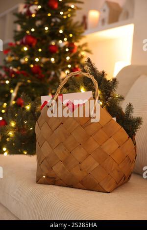 Cestino in vimini con decorazioni natalizie sul divano al coperto Foto Stock