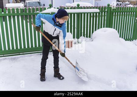 Un adolescente scaglia la nuova neve da un sentiero. Inizio dell'inverno in Austria Foto Stock