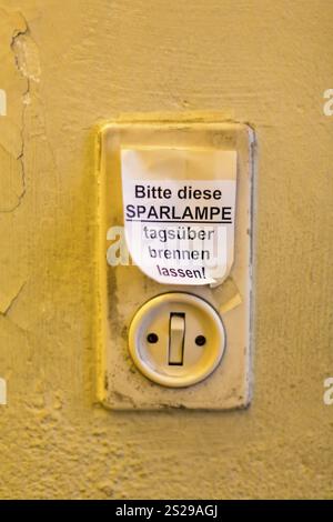 Vecchio interruttore luminoso con etichetta, lasciare accesa la lampadina a risparmio energetico durante il giorno Foto Stock