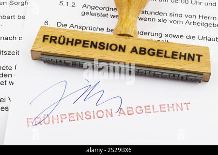 Un timbro di legno giace su un documento. Iscrizione tedesca: Fruehpension abgelehnt Austria Foto Stock