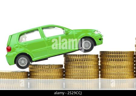 Un'auto modello si erge sulle monete. Aumento dei costi delle auto per benzina, assicurazione e tasse. Austria Foto Stock