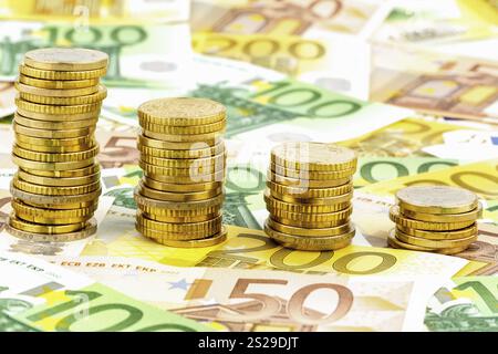 Pila di monete, curva discendente, foto simbolica per il calo dei tassi di interesse e dei costi Foto Stock