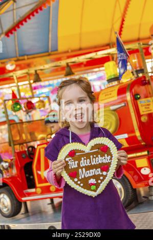 Un bambino ha un cuore fatto di pan di zenzero. Iscrizione: Per la cara mamma. Foto simbolica per la festa della mamma in Austria Foto Stock