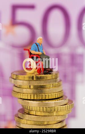 Donna in sedia a rotelle su mucchio di soldi, foto simbolica per disabilità, indennità di assistenza e costi in assistenza sanitaria Austria Foto Stock