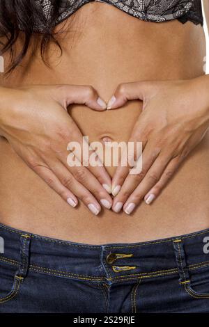 Una giovane donna fa un cuore sullo stomaco con le mani. Foto simbolica per Love Austria Foto Stock