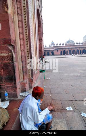 Un musulmano indiano con i capelli tinti con l'henné seduto fuori dalla porta di Buland Darwaza a Fatehpur Sikri, Uttar Pradesh, India. Foto Stock