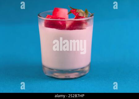 Un bicchiere di latte aromatizzato alla fragola. Il bicchiere è mezzo pieno. Ci sono fragole sopra il latte Foto Stock
