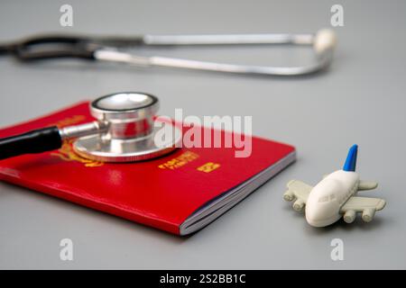 Un'immagine ravvicinata di un passaporto, uno stetoscopio e un aereo giocattolo. Turismo medico o il concetto di viaggiare per il concetto di assistenza sanitaria. Foto Stock