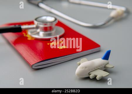 Un'immagine ravvicinata di un passaporto, uno stetoscopio e un aereo giocattolo. Turismo medico o il concetto di viaggiare per il concetto di assistenza sanitaria. Foto Stock