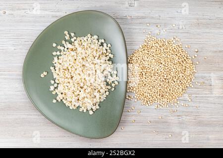 Vista dall'alto dei grani di Sorgo grezzi e del porridge bollito piastra verde su tavolo di legno Foto Stock