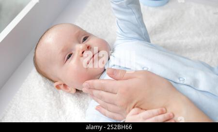 La mano della madre tocca delicatamente la faccia del bambino. Concetto di cura dei bambini, genitorialità e felicità familiare Foto Stock