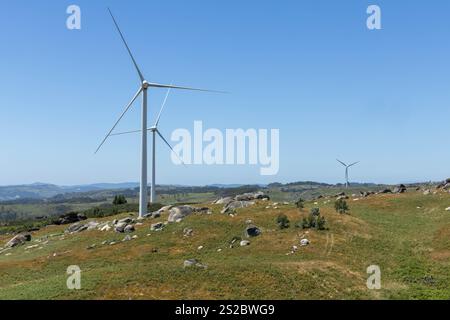 Energia rinnovabile ecocompatibile per le turbine eoliche sulle montagne portoghesi con massi di granito in primo piano Foto Stock