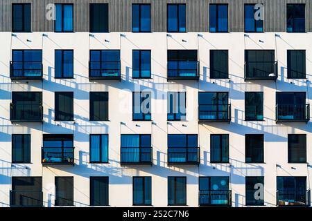 Moderno edificio residenziale con facciata bianca, grandi finestre e balconi che creano ombre uniche Foto Stock