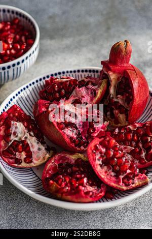 Primo piano di un piatto di melograni freschi aperti su un tavolo con una ciotola di semi di melograno Foto Stock