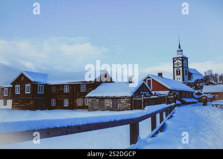 Neve fitta che copre le case colorate di Røros, Norvegia, con l'iconica torre dell'orologio visibile in un giorno d'inverno. Foto Stock