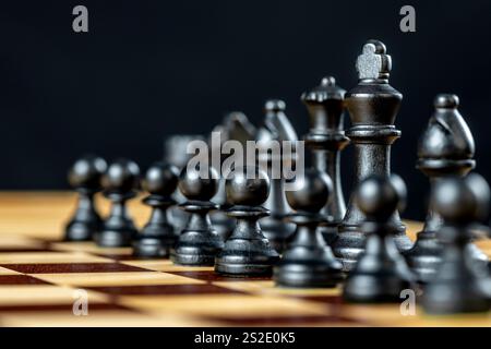Scacchi neri su una scacchiera su sfondo scuro Foto Stock