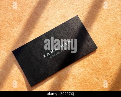 Kiev, Ucraina - 07 gennaio 2025: Una carta Zara Man nera con testo elegante si appoggia su una superficie leggera e strutturata, illuminata dalla luce soffusa del sole che crea sh Foto Stock