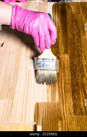 mano guanto colori legno tavola con macchia di legno da pennello a casa Foto Stock