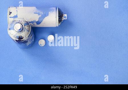 Alcuni hanno usato il blu di aerosol bombolette spray e gli ugelli con gocce di vernice giace su una coperta di soffice e peloso luce blu in tessuto di pile. Classic Design femmina col Foto Stock