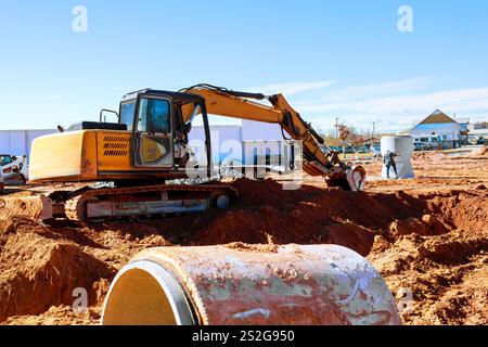 L'escavatore pesante opera nel cantiere, spostando il terreno durante la preparazione del terreno per nuove strutture. Foto Stock