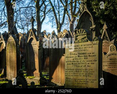 Lapidi nel cimitero illuminato dal sole della chiesa di St Michael All Angels a Haworth, Bronte Country, West Yorkshire. REGNO UNITO Foto Stock