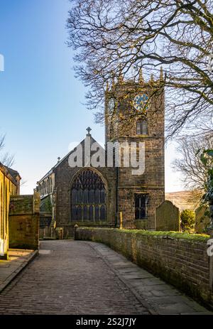 St Michael All Angels Church a Haworth, West Yorkshire, vista da Church Street con la Old School a sinistra. REGNO UNITO Foto Stock