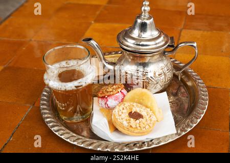 Tè alla menta servito a Marrakech, Marocco. La bevanda è una bevanda popolare in Marocco ed è servita qui con prodotti di pasticceria. Foto Stock