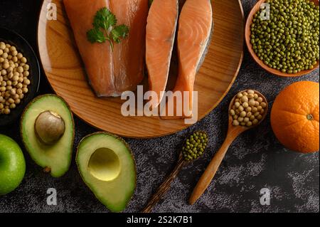 Legumi, frutta e salmone su un piatto di legno. Foto Stock