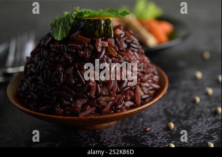 Bacche di riso viola cotte in un piatto di legno con foglie di menta. Messa a fuoco selettiva Foto Stock