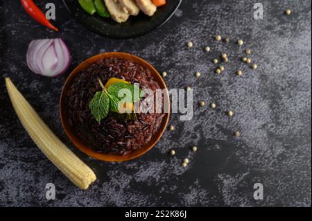 Bacche di riso viola cotte in un piatto di legno con foglie di menta. Messa a fuoco selettiva Foto Stock