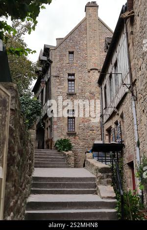 180 Mont-Saint-Michel: Pareti in muratura di granito e facciate a graticcio su edifici all'estremità nord della grande Rue-Main Street. Normandia-Francia. Foto Stock
