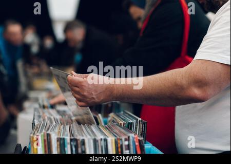 Primo piano di un uomo che sceglie un vinile al mercato del vinile. Scelta dei dischi in vinile in negozio. Dischi in vendita in un negozio di vinile vintage. Foto Stock