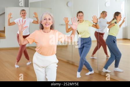 Donna anziana che impara danza aerobica con i suoi parenti più giovani Foto Stock