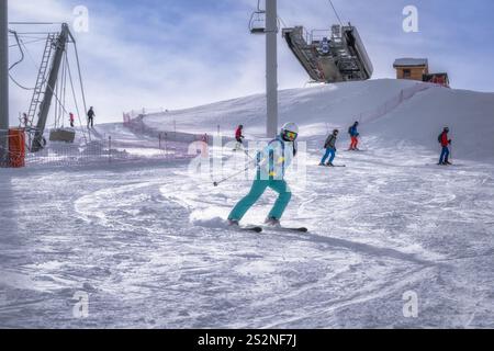 Questa splendida scena invernale presenta sciatori gioiosi di tutte le età che si divertono sulle piste innevate, rendendolo una destinazione perfetta per gli amanti degli sport invernali in cerca di avventura, Montgenevre, Alpi, Francia Foto Stock